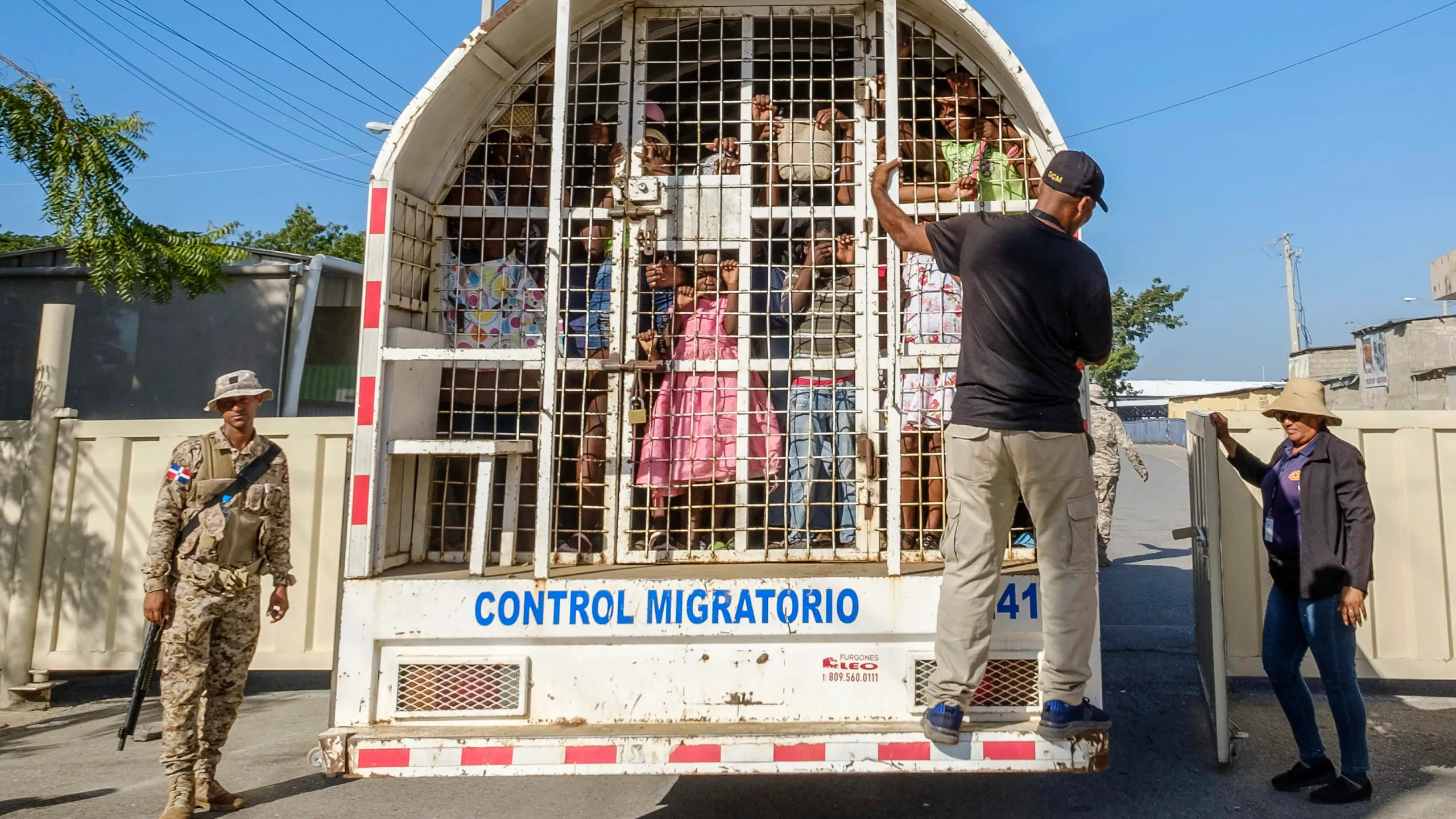 A Dominican migration control vehicle with people, including children, held inside