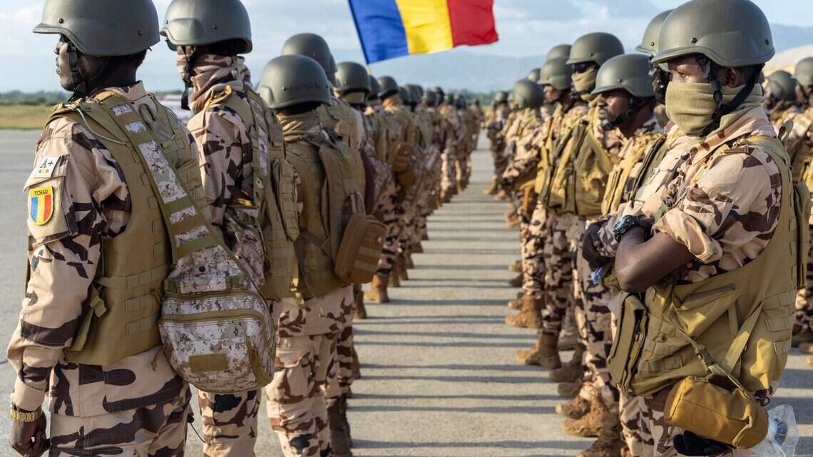 Chadian soldiers in desert camouflage standing in formation with the flag of Chad