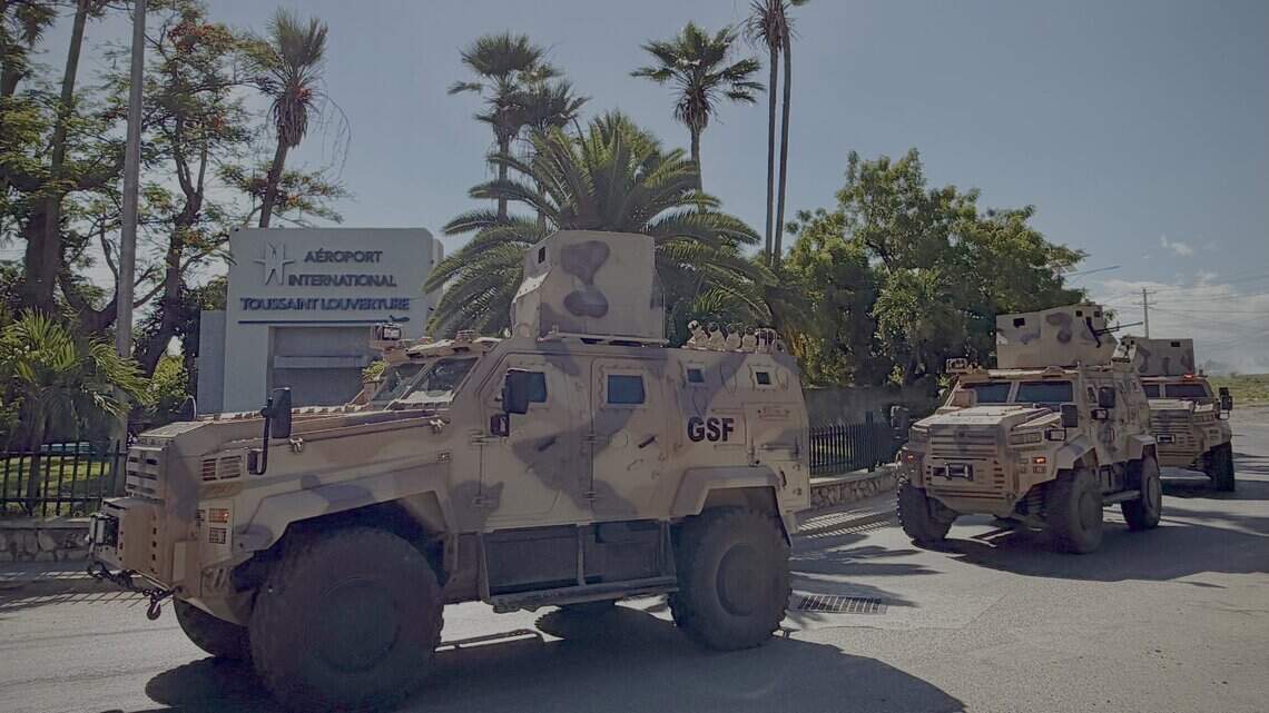 Desert-camouflage armoured vehicles marked GSF outside Toussaint Louverture International Airport