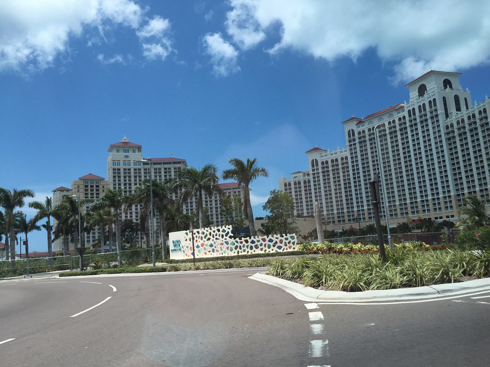 Tall hotel towers of the Baha Mar resort with palm trees and a roadway in front