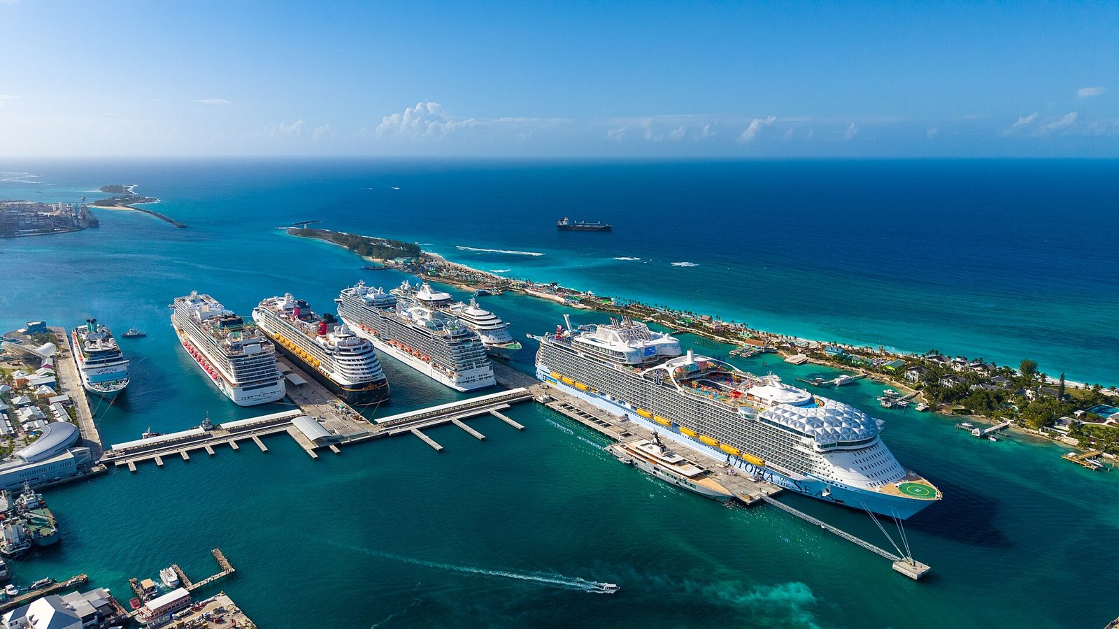Aerial view of several large cruise ships docked at the Nassau Cruise Port with turquoise water and Paradise Island in the distance