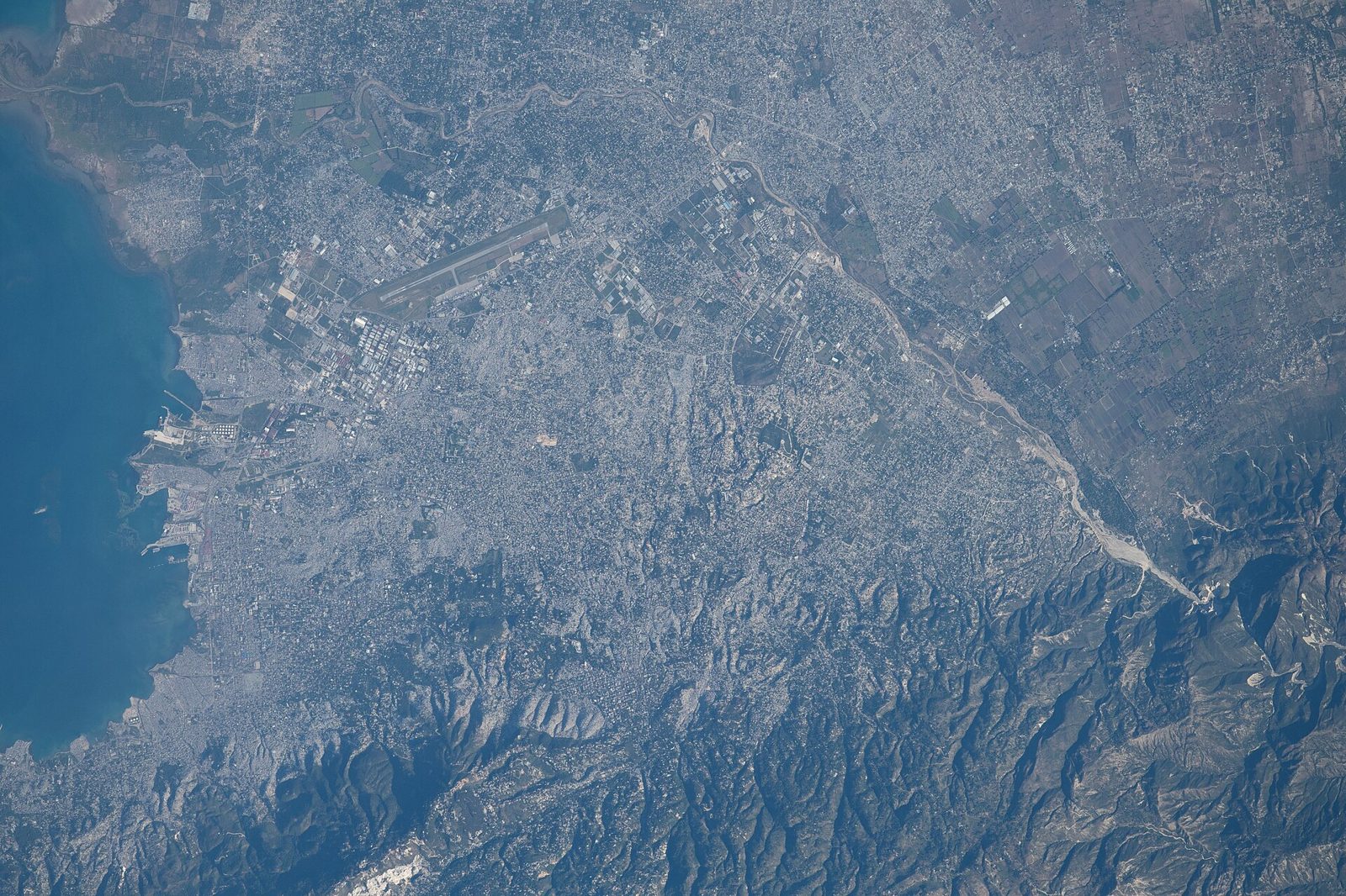 View from high above of Port-au-Prince with the bay on the left and dense city streets spreading toward green hills