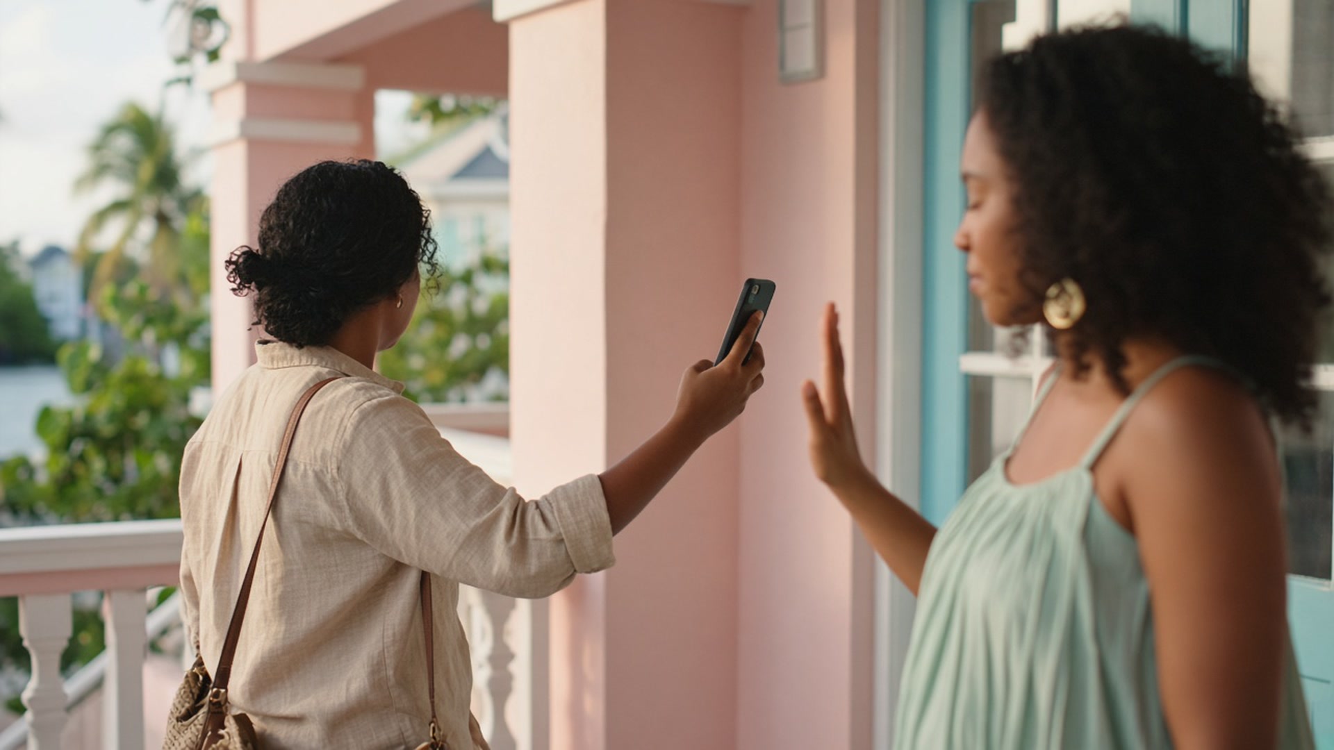 Two women on a porch, one offering a phone, the other pausing